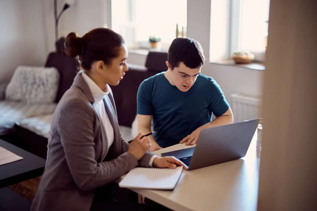 Support worker and disabled man looking at laptop