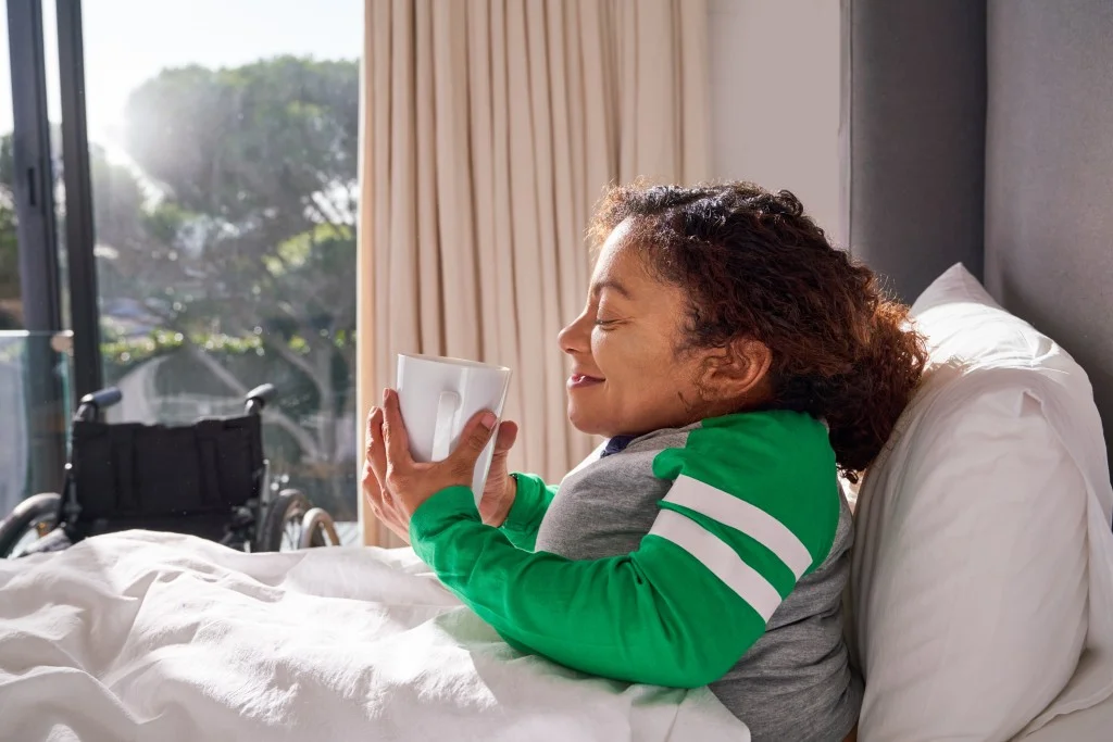 Disabled woman in bed enjoying cup of tea