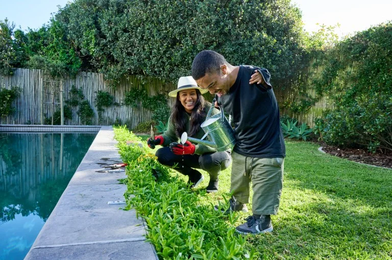 Support worker and disabled man watering garden